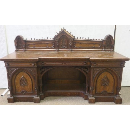 614 - A GOTHIC DESIGN OAK PEDESTAL SIDEBOARD of inverted breakfront outline the superstructure with carved... 