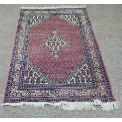 618 - AN ORIENTAL WOOL RUG the light pink and light blue ground with central serrated panel within a confo... 