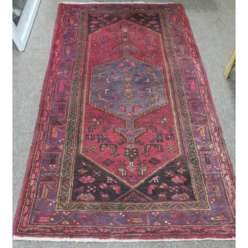 721 - AN ORIENTAL WOOL RUG the wine and light blue ground with central serrated panel filled with stylised... 