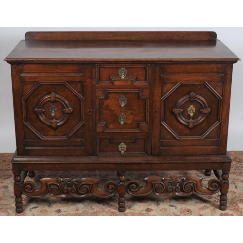 744 - A JACOBEAN DESIGN OAK AND WALNUT SIDEBOARD of rectangular outline the shaped top above four frieze d... 