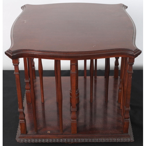 94 - A VINTAGE MAHOGANY TABLE TOP REVOLVING BOOKCASE of serpentine outline the shaped top above open comp... 