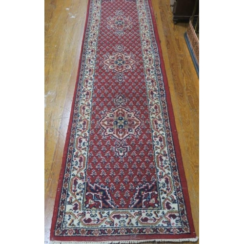 402 - A SEROUK WOOL RUNNER the wine ground with central panel filled with stylised flowerheads and foliage... 