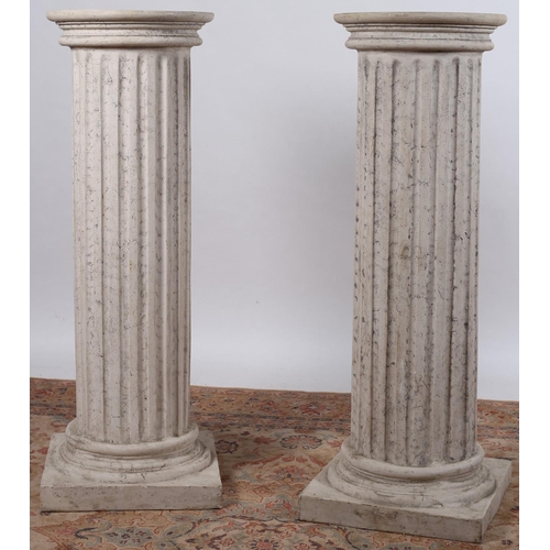 64 - A PAIR OF COMPOSITION PEDESTALS each of circular outline the shaped tops above fluted columns on mou... 