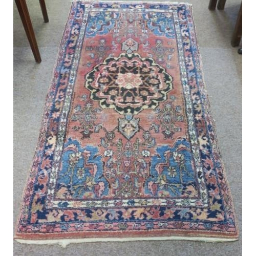 552 - A TRIBAL WOOL RUG the light pink ground with central panel filled with stylised flowerheads and foli... 