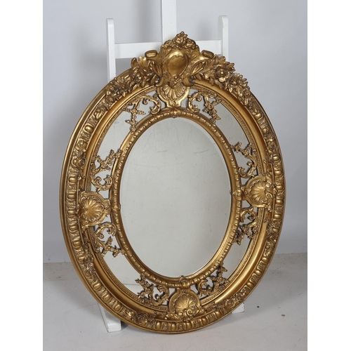 350 - A CONTINENTAL GILT FRAME MIRROR of oval outline the gadrooned and flowerhead decorated frame with sh... 