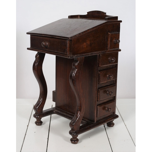 713 - A MINIATURE STAINED WOOD DAVENPORT of typical form with frieze drawer flanked by four short drawers ... 