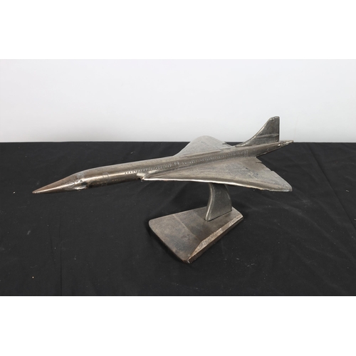 125 - A CAST WHITE METAL FIGURE modelled as a concorde on a shaped platform base 
24cm (h) x 61cm (w) x 24... 