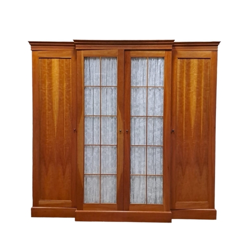 205 - A CHERRYWOOD BREAKFRONT WARDROBE the moulded cornice above a pair of glazed doors containing hanging... 