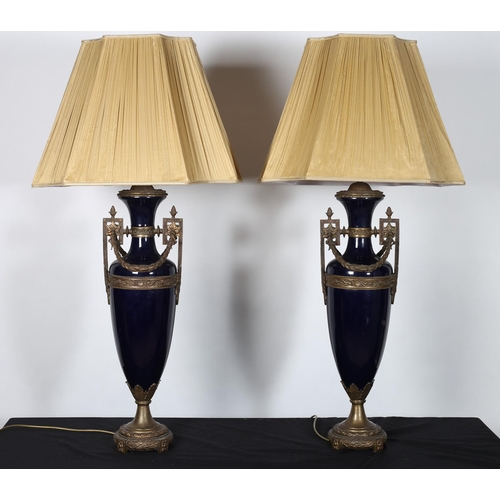 285 - A PAIR OF CONTINENTAL GILT BRASS AND FLOW BLUE TABLE LAMPS each of urn form hung with laurel wreaths... 