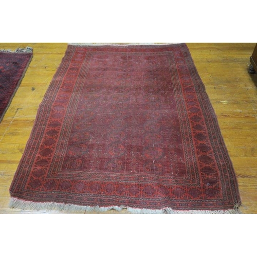 361 - AN ORIENTAL WOOL RUG the wine ground with central panel filled with geometric panels within a confor... 