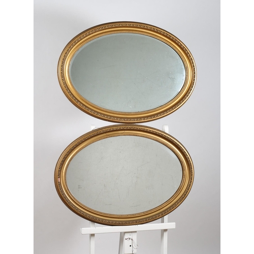 744 - TWO OVAL GILT FRAME MIRRORS together with a rectangular bevelled glass mirror in a stained wood and ... 