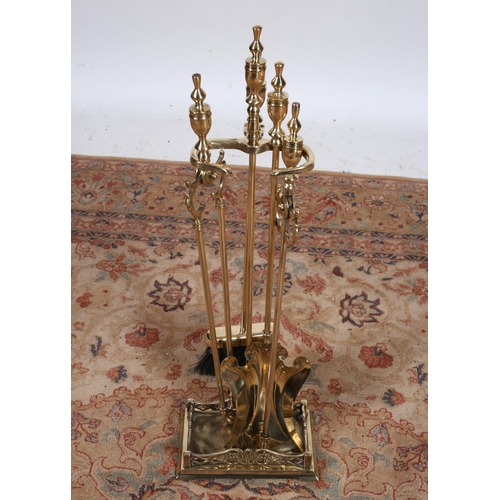 67 - A BRASS FOUR PIECE COMPANION SET on stand comprising poker, shovel, tongs and brush with urn finial ... 