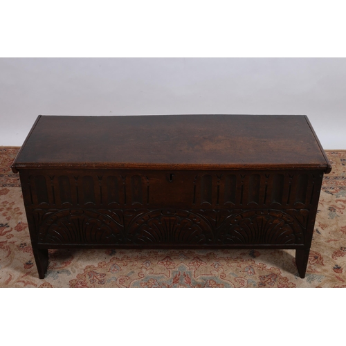 92 - A JACOBEAN DESIGN CARVED OAK TRUNK of rectangular outline the hinged lid above a stop fluted carved ... 