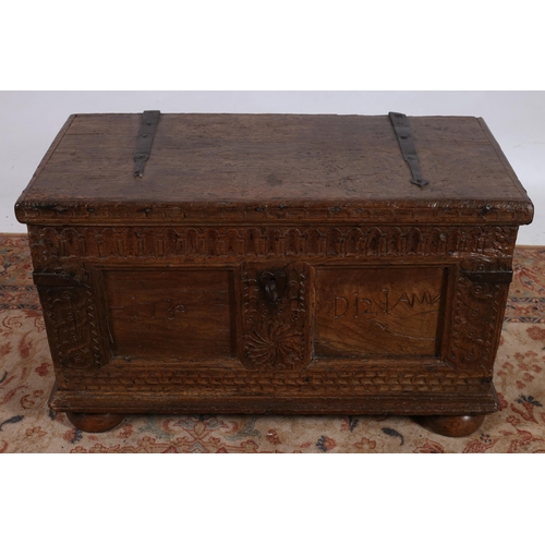 185 - AN EARLY OAK COFFER of rectangular outline the shaped hinged lid with metal straps containing a lidd... 