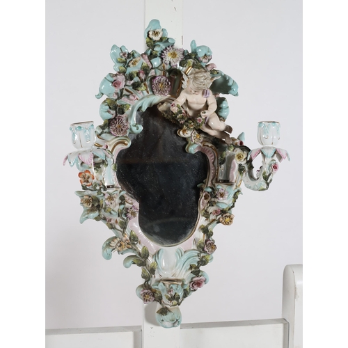 225 - A PAIR OF CONTINENTAL PORCELAIN FLOWER ENCRUSTED GIRANDOLE MIRRORS surmounted by winged cherubs abov... 