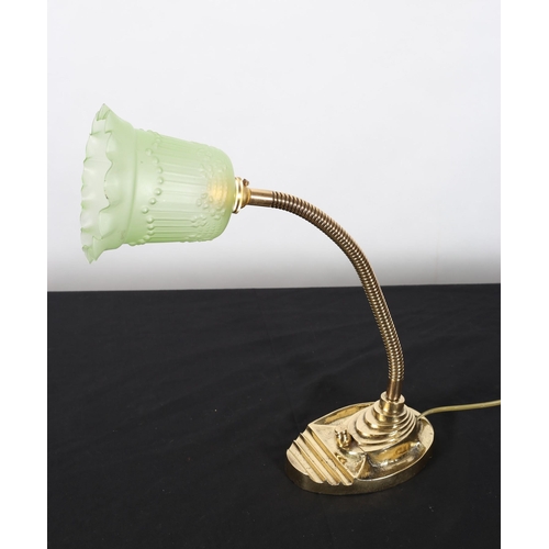 555 - A BRASS DESK TABLE LAMP with adjustable arm raised on an oval shaped base with green moulded glass s... 