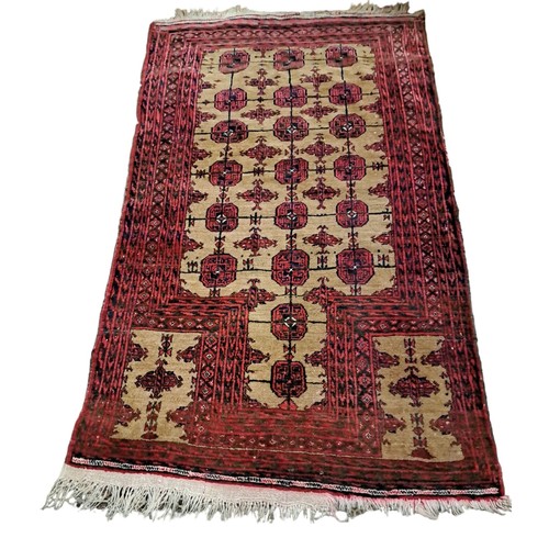 578 - AN ORIENTAL WOOL RUG the light brown and wine ground with central panels with canted angles within a... 