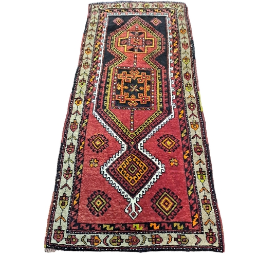 583 - A TIBRIZ WOOL RUG the red ground with central panels filled with hooks and palmets within a conformi... 