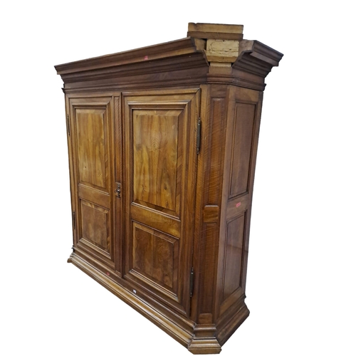 642 - A 19TH CENTURY WALNUT ARMOIRE the moulded cornice above a pair of raised panel doors containing hang... 