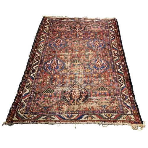 741 - AN IRANIAN WOOL RUG the indigo and wine ground filled with serrated panels, flowerheads and hooks wi... 