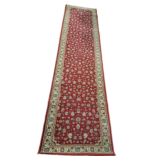 150 - A WOOL RUNNER the wine ground with central stylised floral panel within a conforming border 
350cm (... 