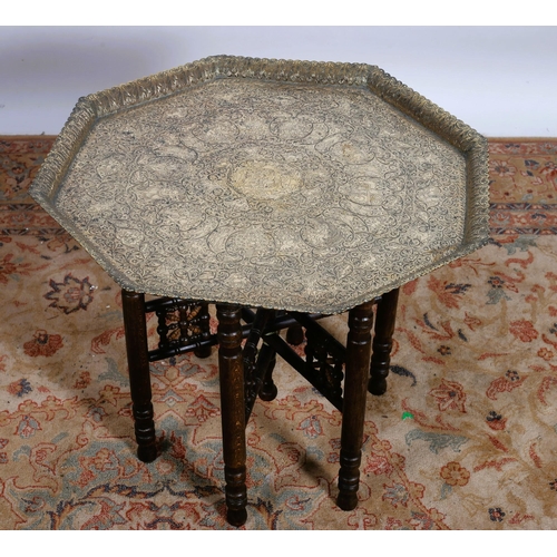 191 - A VINTAGE BRASS ENGRAVED BENARES TRAY of octagonal form the shaped tray raised on a folding stand to... 