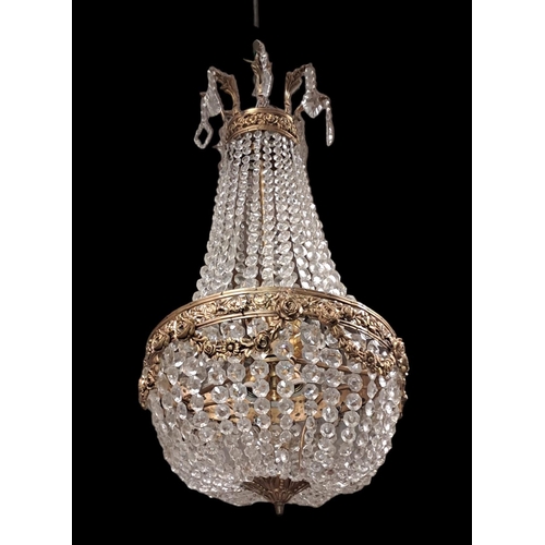 267 - A CONTINENTAL GILT BRASS AND CUT GLASS CHANDELIER hung with cascading pendent drops the foliate cast... 