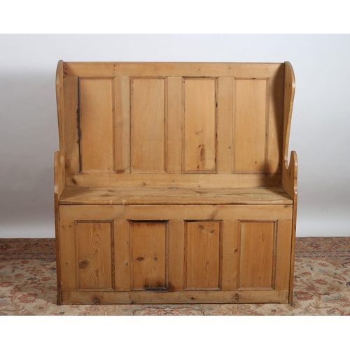 283 - A VINTAGE PINE WING BACK BENCH with panelled splats above a hinged seat with conforming apron on mou... 