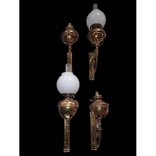 352 - A SET OF FOUR 19TH CENTURY BRASS WALL MOUNTED OIL LAMPS each with a rectangular back plate with scro... 