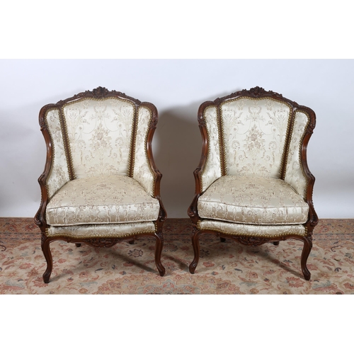 414 - A PAIR OF CONTINENTAL MAHOGANY AND UPHOLSTERED ARMCHAIRS each with a foliate carved top rail above b... 