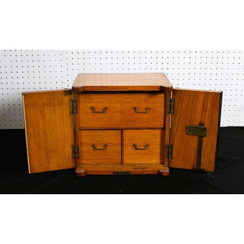 494 - A 19TH CENTURY OAK MINIATURE CHEST in the form of a safe of rectangular outline the shaped top above... 