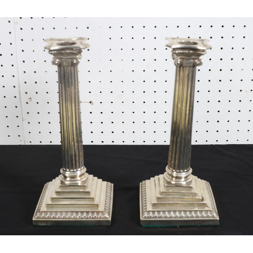 520 - A PAIR OF SILVER CANDLESTICKS each with a reeded column and ionic capital above a square stepped bas... 