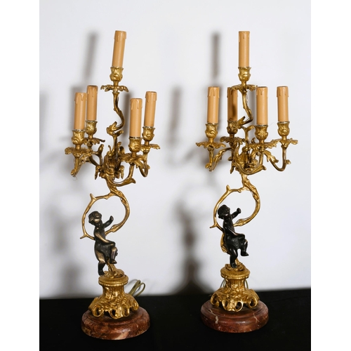 587 - A PAIR OF CONTINENTAL GILT BRASS AND BRONZE FIVE BRANCH CANDELABRA the foliate cast scroll arms and ... 