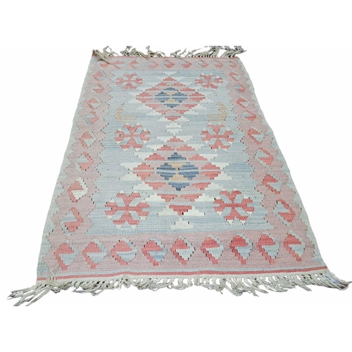 747 - AN ORIENTAL WOOL RUG the light pink and indigo ground with central panel filled with serrated panels... 