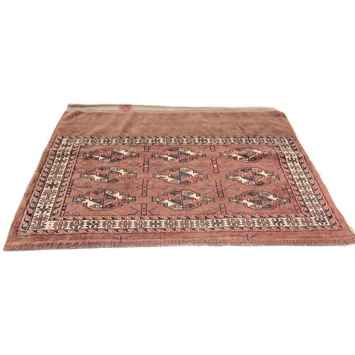 748 - AN ORIENTAL WOOL RUG the central panel filled with geometric panels within a serrated and hook borde... 