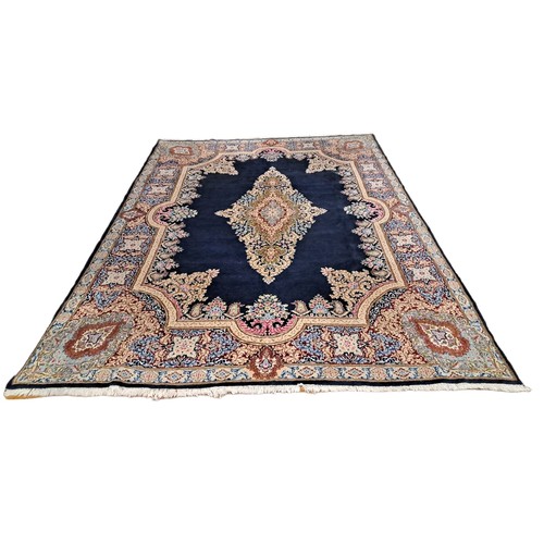 571 - A KERMAN WOOL RUG the indigo ground with central floral panel within a conforming border 
385cm (l) ... 