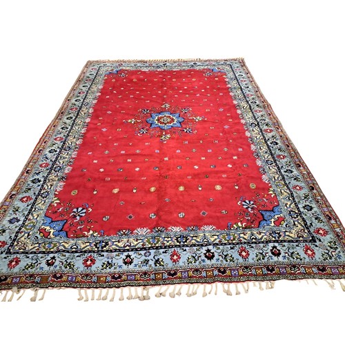 576 - A MOROCCAN ROYAL RABAT WOOL RUG the red ground with central panel filled with stylised flowerheads, ... 