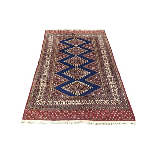 582 - A KAZAK TURKISH WOOL RUG the indigo and wine ground with central diamond shaped panels within a conf... 