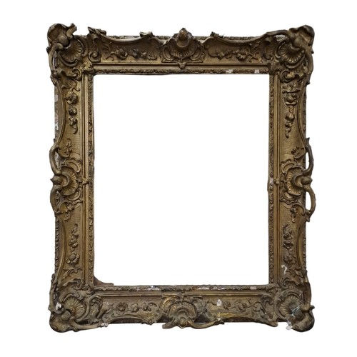 607 - A 19TH CENTURY GILTWOOD AND GESSO GILT FRAME moulded in high relief with stylised flowerheads, folia... 