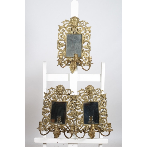 299 - A SET OF FOUR VINTAGE BRASS GIRANDOLE WALL MIRRORS each with a pierced foliate scroll frame with fig... 