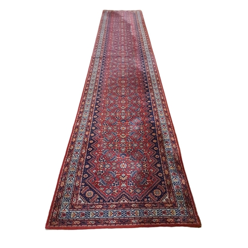 164 - AN ORIENTAL WOOL RUNNER the light red and indigo ground with central panel filled with serrated pane... 