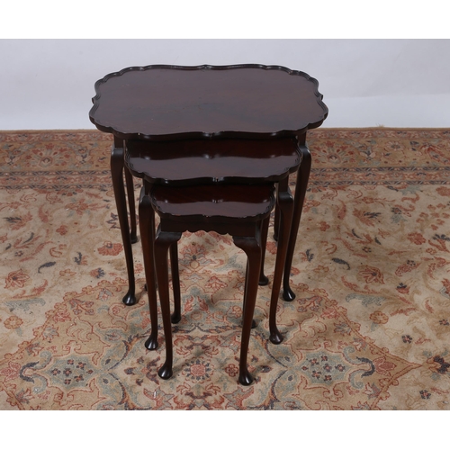 199 - A NEST OF THREE VINTAGE MAHOGANY TABLES each of a serpentine outline the shaped top with moulded gal... 