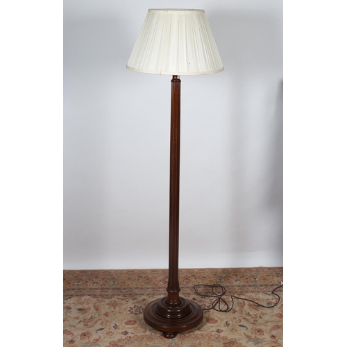 214 - A VINTAGE MAHOGANY STANDARD LAMP the reeded column above a circular spreading foot with pleated shad... 