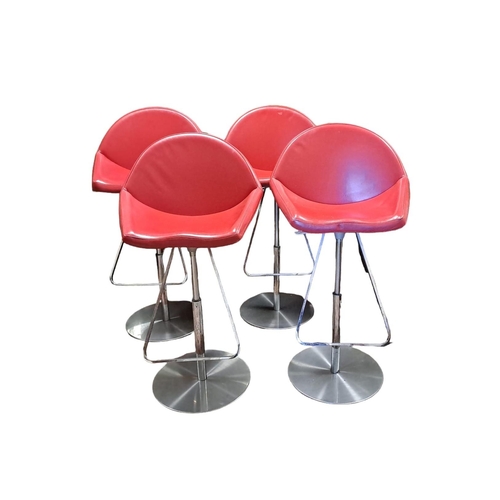 227 - A SET OF FOUR CHROME AND RED HIDE UPHOLSTERED SWIVEL STOOLS the arched back with shaped seats raised... 