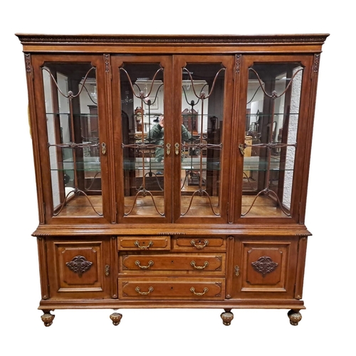 235 - A CONTINENTAL MAHOGANY DISPLAY CABINET the foliate carved cornice above glazed doors containing glaz... 