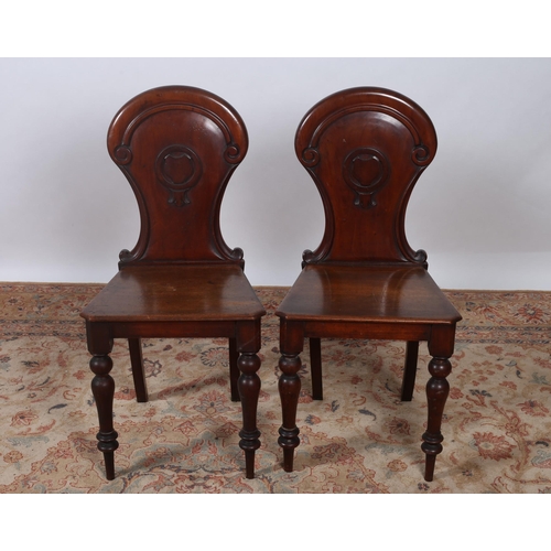 238 - A PAIR OF 19TH CENTURY MAHOGANY HALL CHAIRS each with a shield shaped back and panel seat on baluste... 