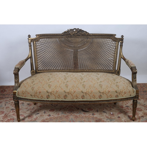 250 - A CONTINENTAL GILTWOOD AND UPHOLSTERED SETTEE the ribbon frame with musical trophy cresting above a ... 