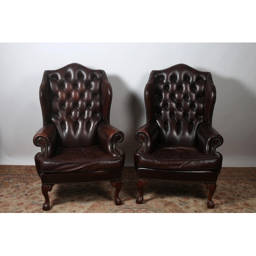 324 - A PAIR OF GEORGIAN DESIGN MAHOGANY AND HIDE UPHOLSTERED WING CHAIRS with deep buttoned upholstered b... 