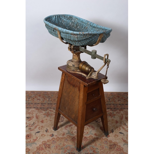 326 - A VINTAGE CAST IRON AND WICKER CHILD'S WEIGH SCALES raised on a moulded pedestal with two frieze dra... 