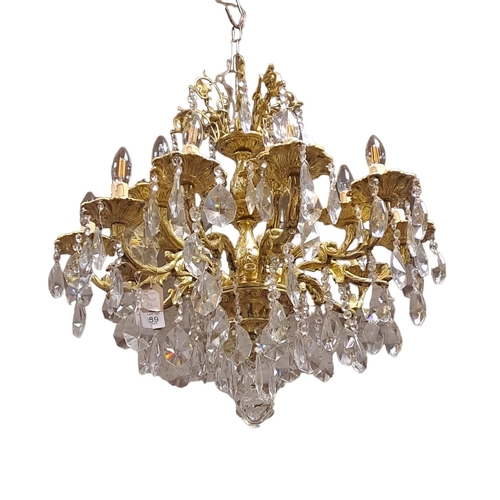 389 - A CONTINENTAL GILT BRASS AND CUT GLASS TWELVE BRANCH CHANDELIER in two registers the foliate cast sc... 